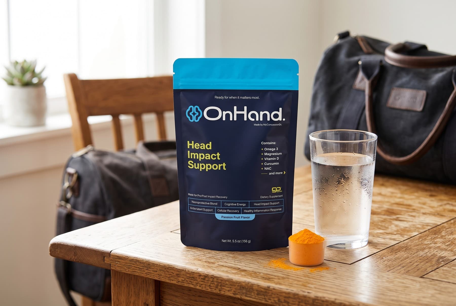 The OnHand pouch standing on a wooden kitchen table in morning light beside a glass of water and a scoop of orange powder, with a gym bag on a chair behind